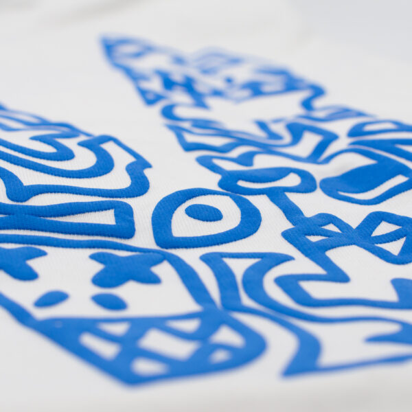 Detalle de estampado azul en relieve sobre tela blanca, con ilustraciones abstractas y una calavera estilizada.