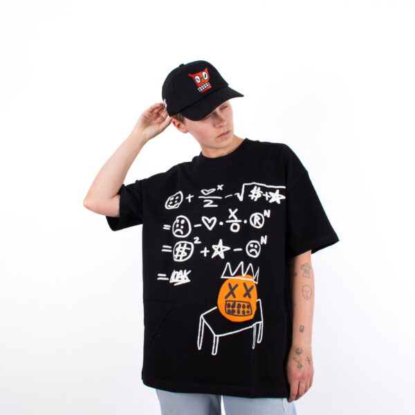 Camiseta negra con ilustraciones blancas y calavera naranja, usada por persona con gorra negra y tatuajes en los brazos.