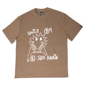Camiseta marrón con ilustración blanca de un rostro sonriente y la frase 'SMILE B4 SAD AGAIN'.