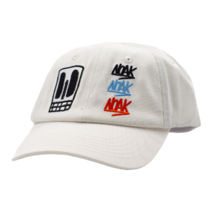 Gorra blanca con bordados de calavera negra y tres logos 'NOAK' en negro, azul y rojo.