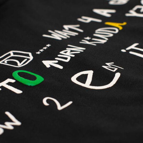 Detalle de bordado en sudadera negra con tipografía blanca y elementos en verde y amarillo, con textura en relieve.