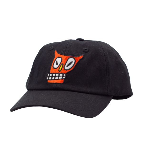 Gorra negra con visera curva y bordado frontal de rostro naranja con ojos grandes y dientes cuadrados.